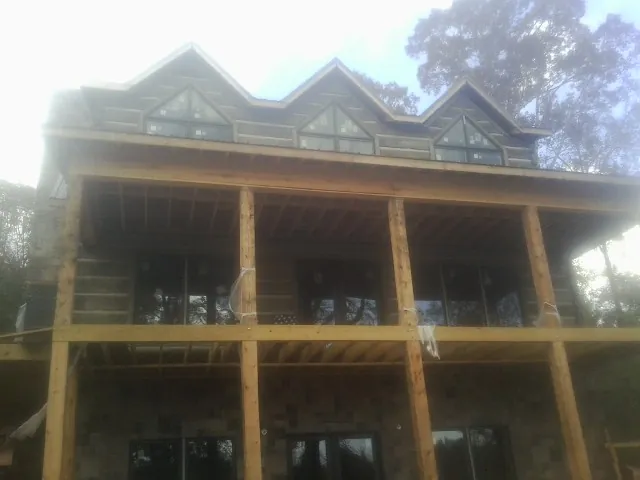 Dormers and porch framing on a large log home under construction — Roof Coating work by our crew in Cedar