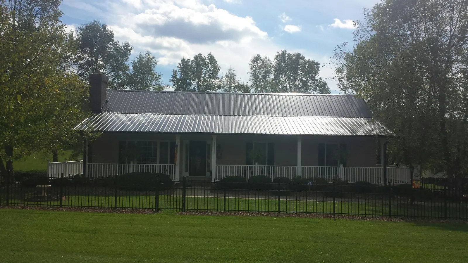Gray metal roof on a brick ranch with a full width front porch — Gutter Guard Installation work by our crew in Cedar